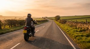 Motorcyclist in full riding gear on a rural British road at golden hour
